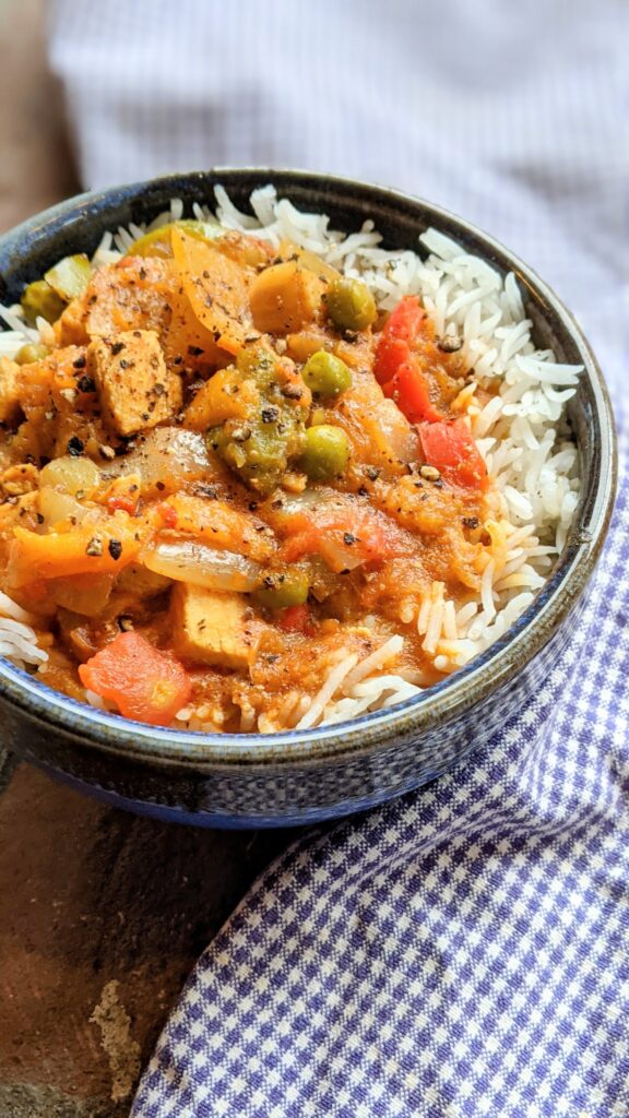 indian chicken du pyaza recipe with onions and vegetables in a creamy tomato sauce over rice