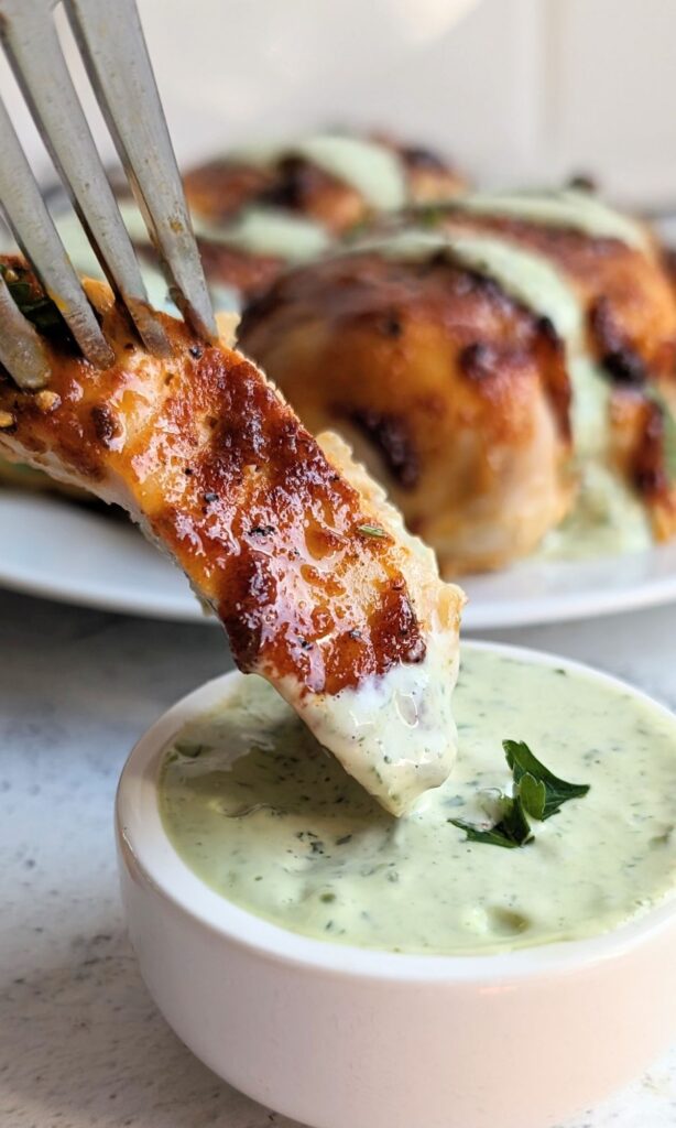 a slice of grilled chicken dipped into a homemade cilantro mayonnaise crema sauce recipe beautiful and flecked with green from the fresh cilantro