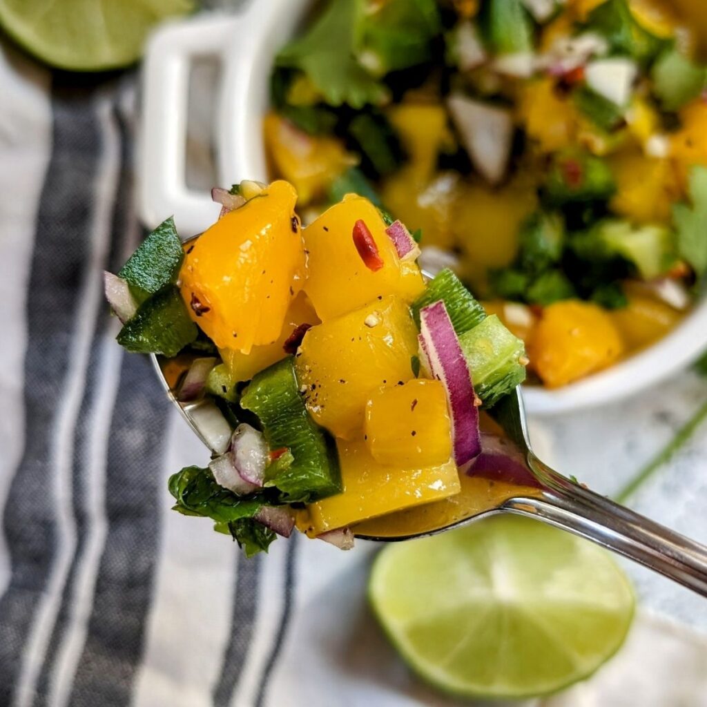 ripe mango salsa with fruit and lime juice on a spoon ready for mahi mahi tacos