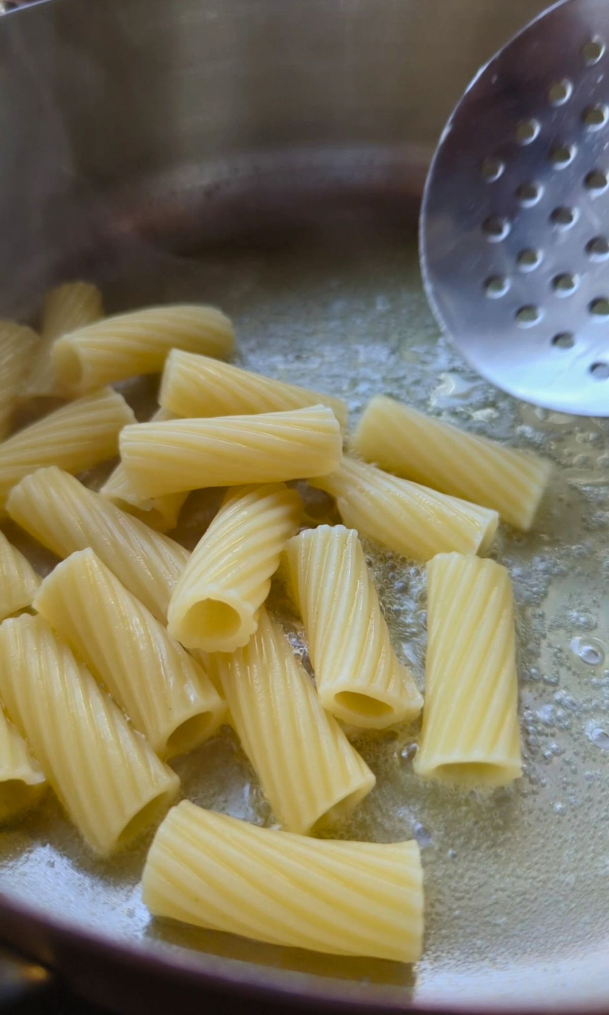 cooked pasta being added to melted butter for cacio e pepe.