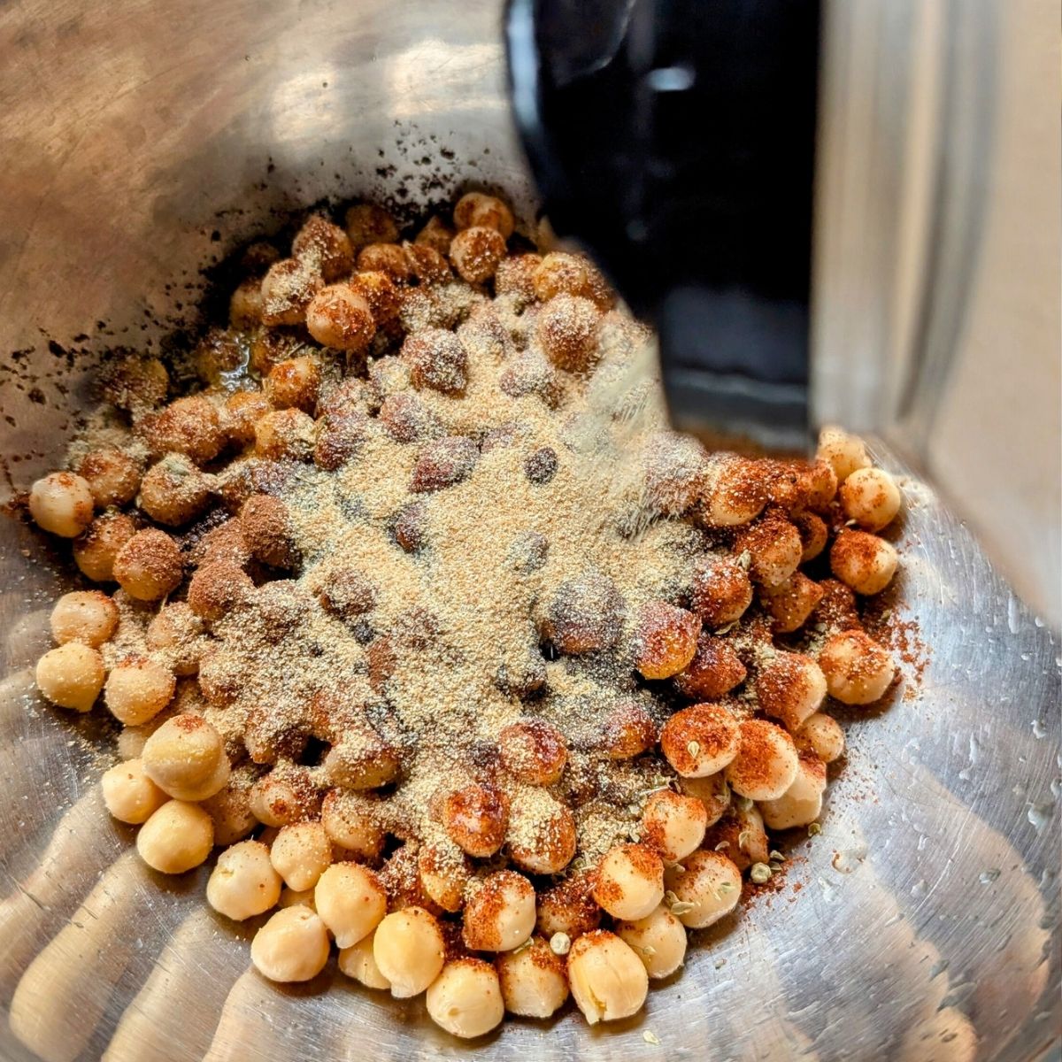 chickpeas being coated in spices like garlic powder, smoked paprika, and chili powder.