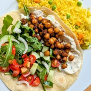 chickpea spiced shawarma recipe on a late in a pita wrap with vegetable toppings and yellow rice.