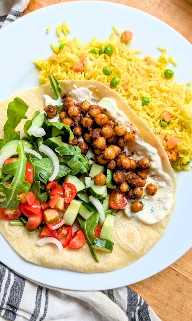 a plate with a chickpea shawarma wrap recipe with a side of yellow rice with turmeric.