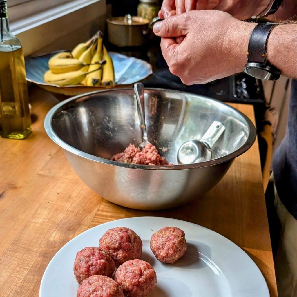 hands rolling balls of brisket meat to make grilled brisket burgers.