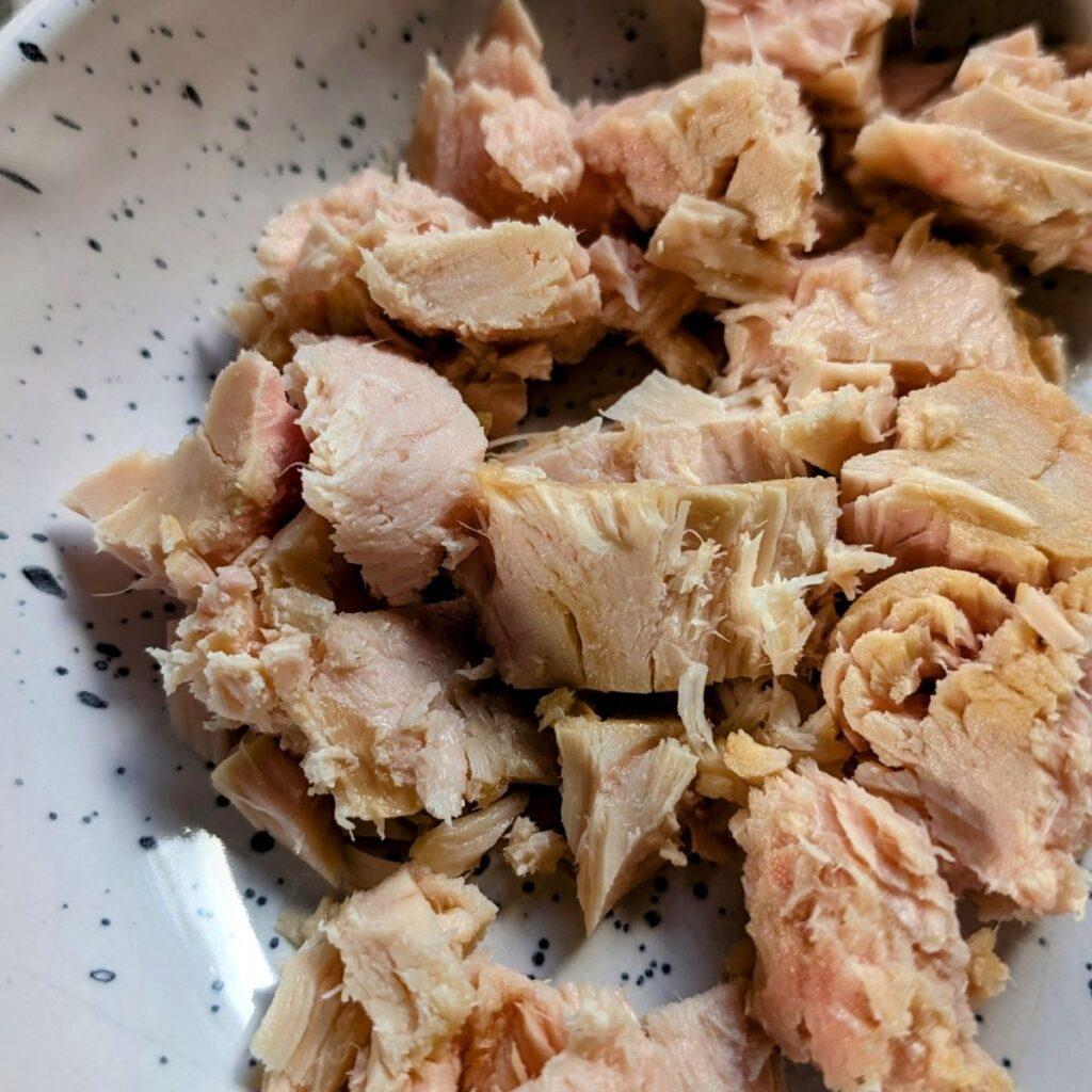 canned albacore tuna packed in water drained and in a mixing bowl to make tuna salad.