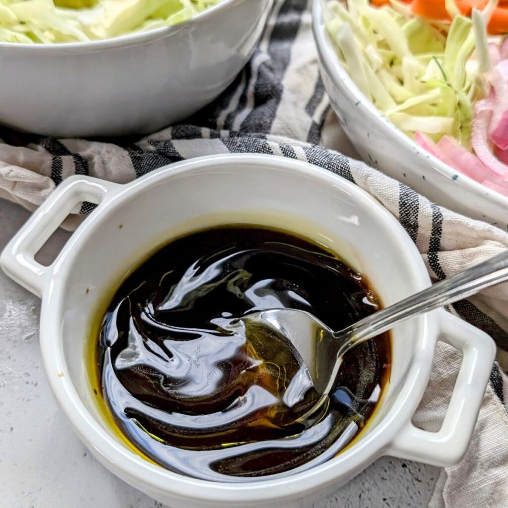 sesame oil and lime dressing for a thai noodle salad bowl being mixed with a spoon.