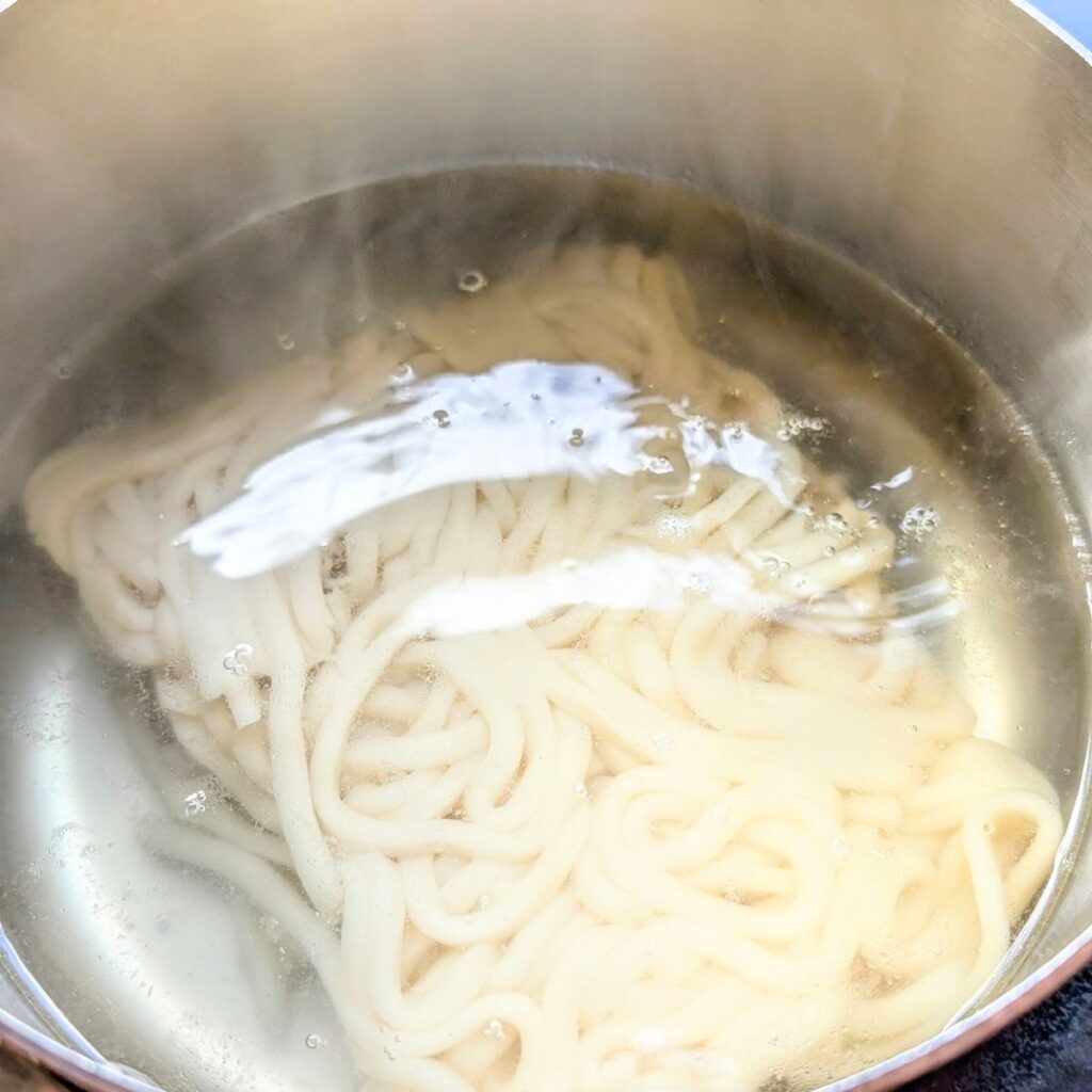 a pot full of boiling water and fresh thai wheat noodles being cooked until tender and springy.