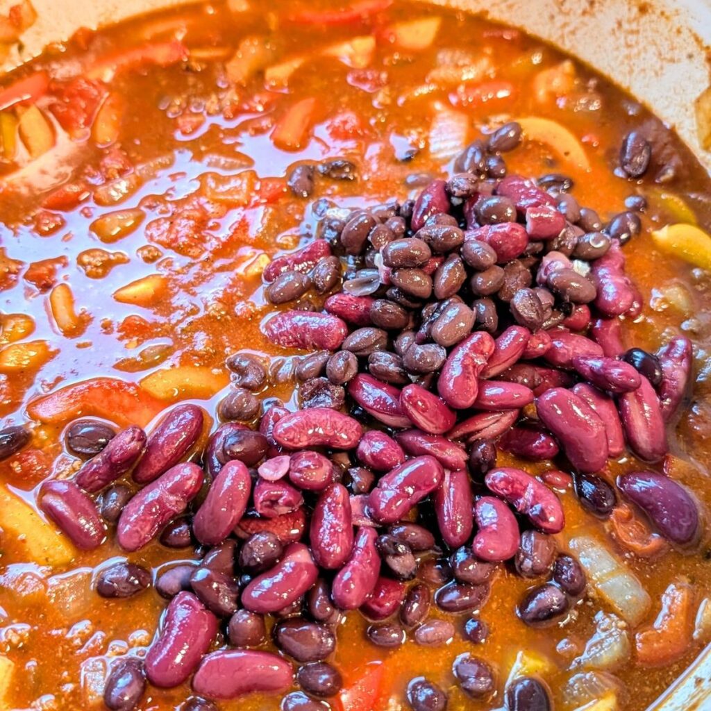 kidney beans and black beans in a pot of buffalo meat chili with veggies.