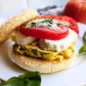 an italian caprese breakfast sandwich with parmesan cheese, mozzarella, tomatoes, and basil.