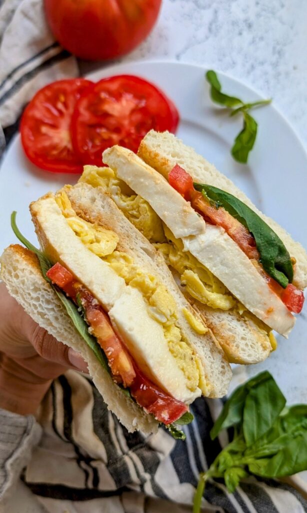 caprese egg sandwich recipe with tomato, basil, and an english muffin bun for an italian meal.