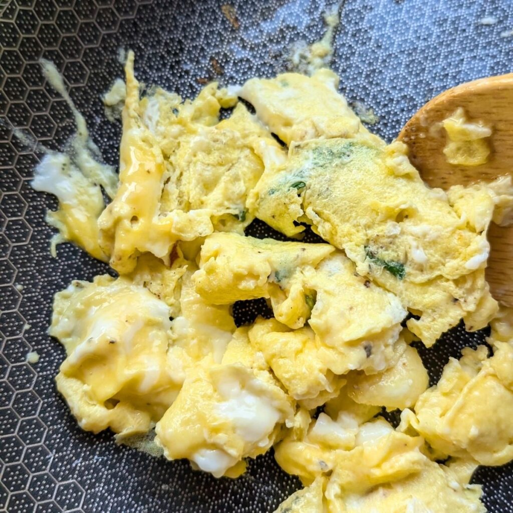 basil and parmesan scrambled eggs in a pan to make an italian breakfast sandwich