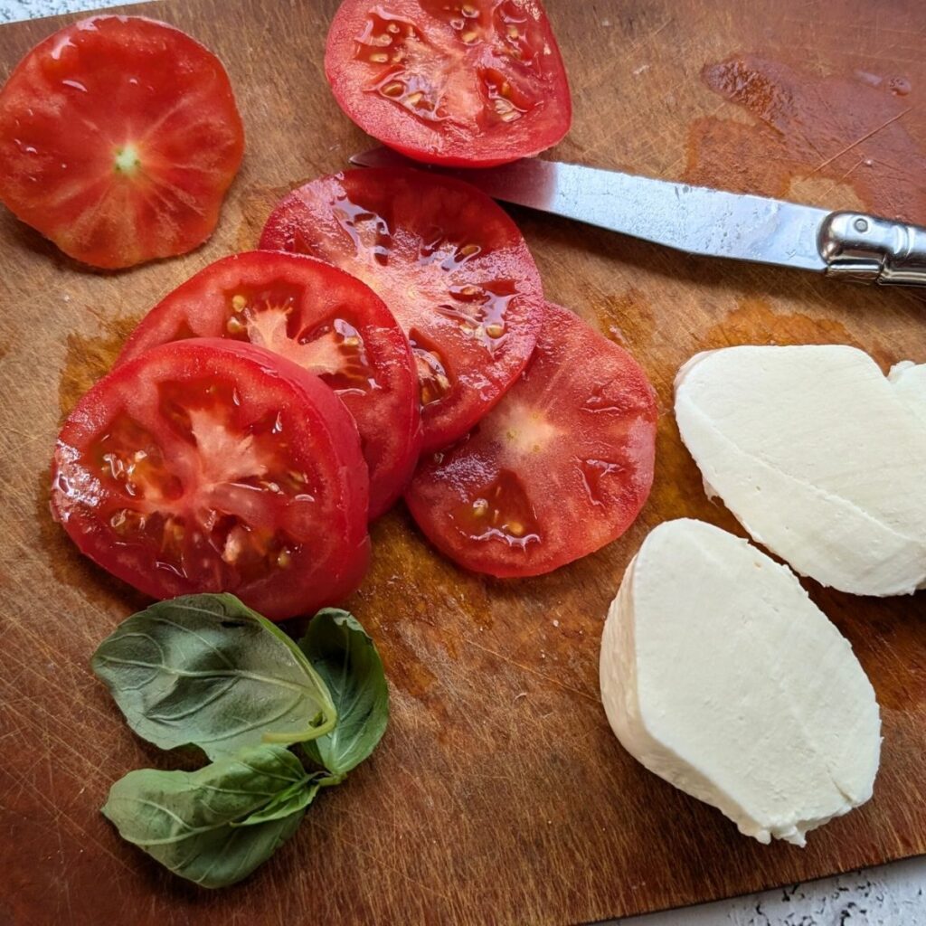 sliced tomatoes, basil, and fresh mozzarella cheese for a breakfast recipe sandwich.