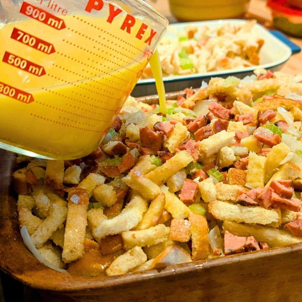 a baking dish of stuffing with sage, chorizo, rosemary, bread, onions, garlic, and butter.