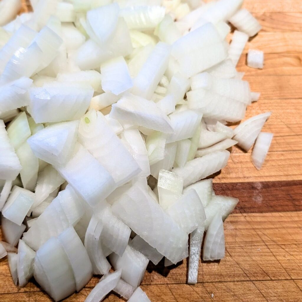 chopped onions on a cutting board getting ready for thanksgiving stuffing