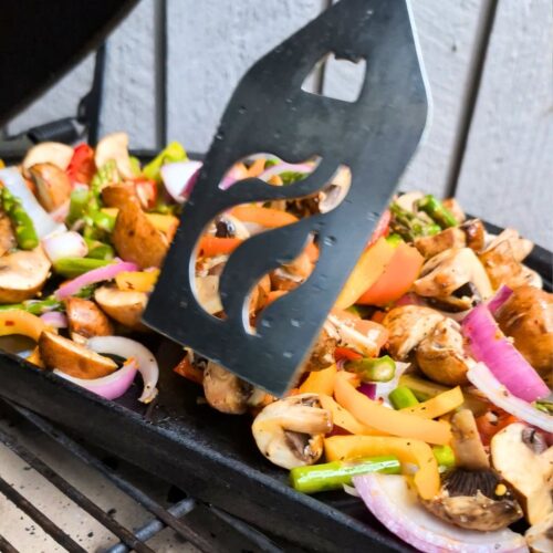 a spatula turning and flipping big green egg vegetables for a side dish