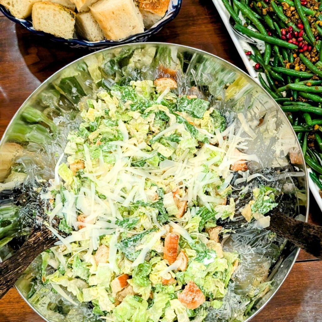 a caesar salad with croissants and parmesan cheese shredded with lettuce.