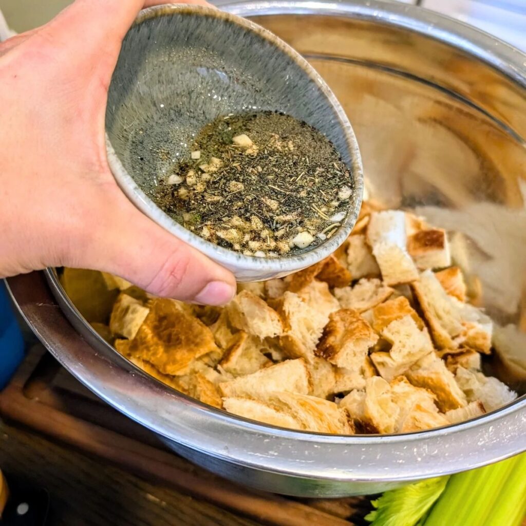 crouton dressing being poured over cubed stale croissants