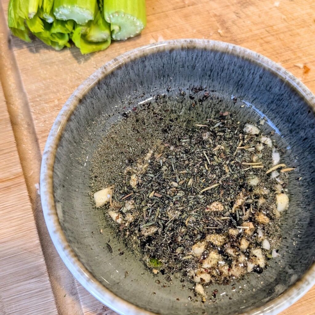 olive oil dressing for croutons in a bowl with dried herbs and fresh garlic.