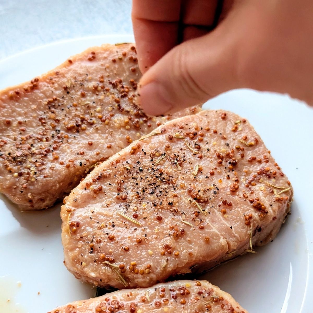 pork chops on a plate with a rosemary and mustard mixture with black pepper