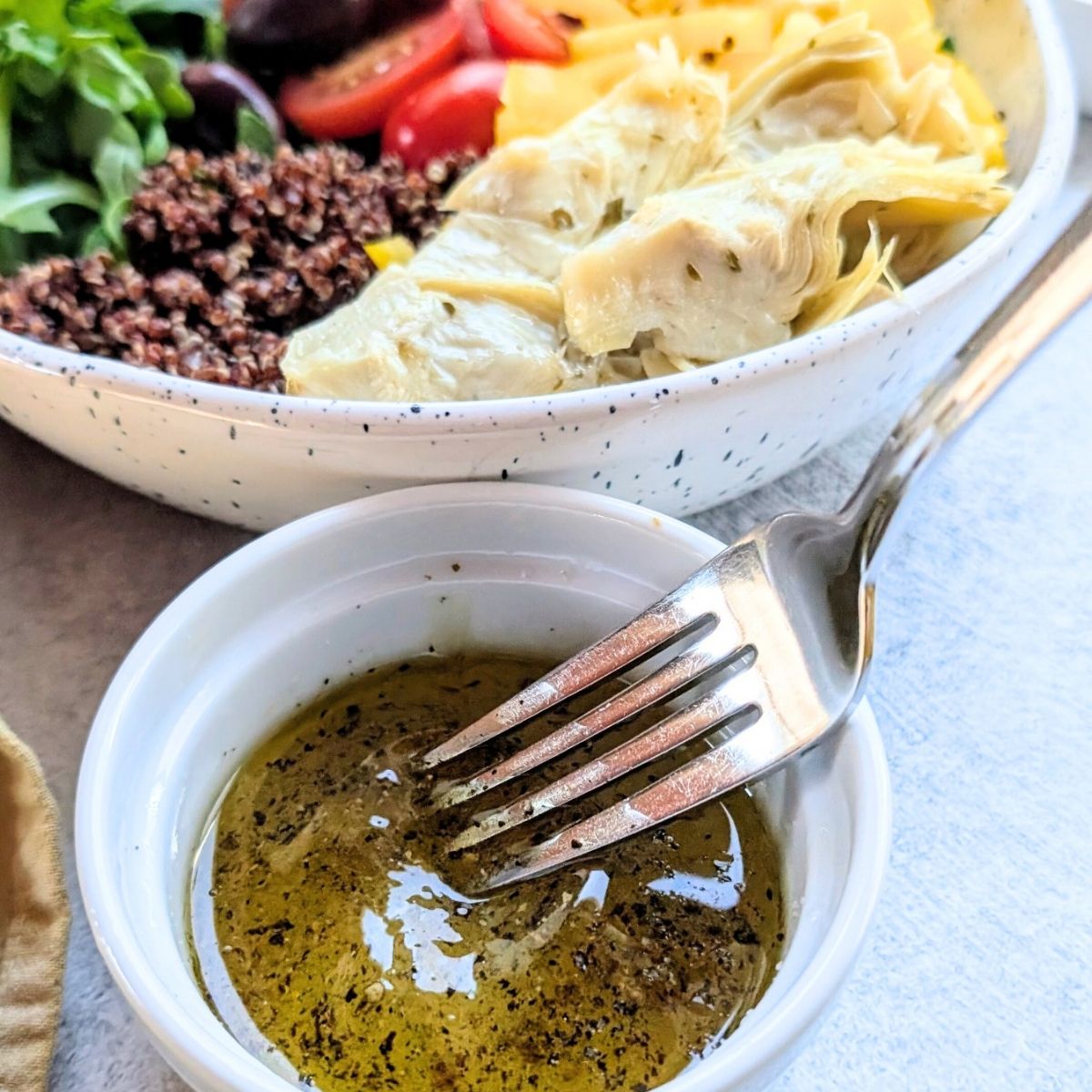 a fork whisking a lemon olive oil vinaigrette salad dressing with salt and pepper.