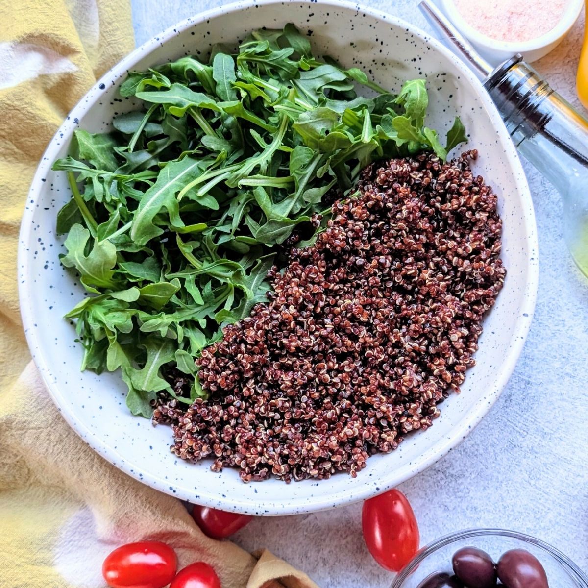 a bowl of quinoa and arugula greens in a bowl with cherry tomatoes