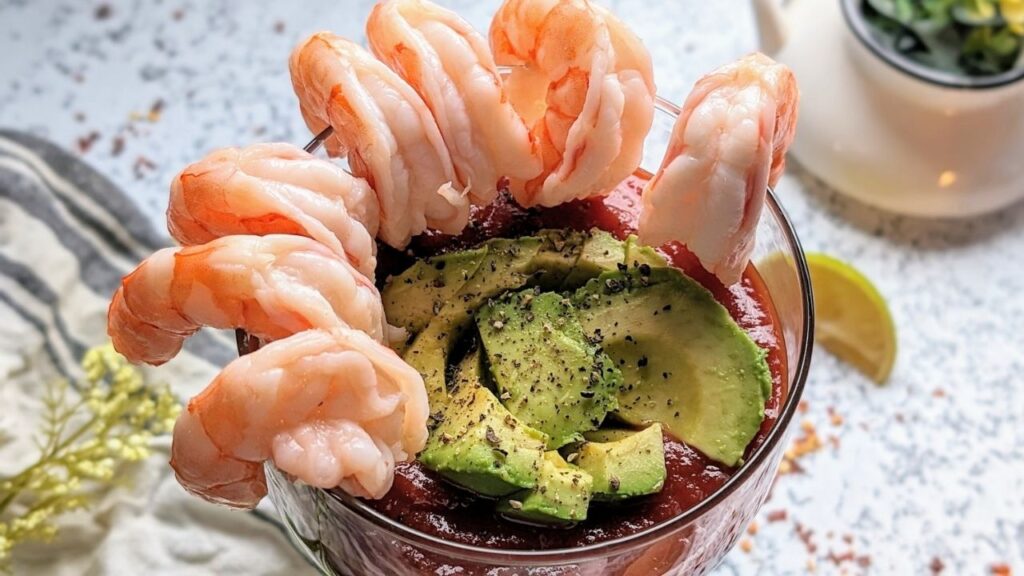 shrimp cocktail in a margarita glass with avocado cocktail sauce and lime juice.