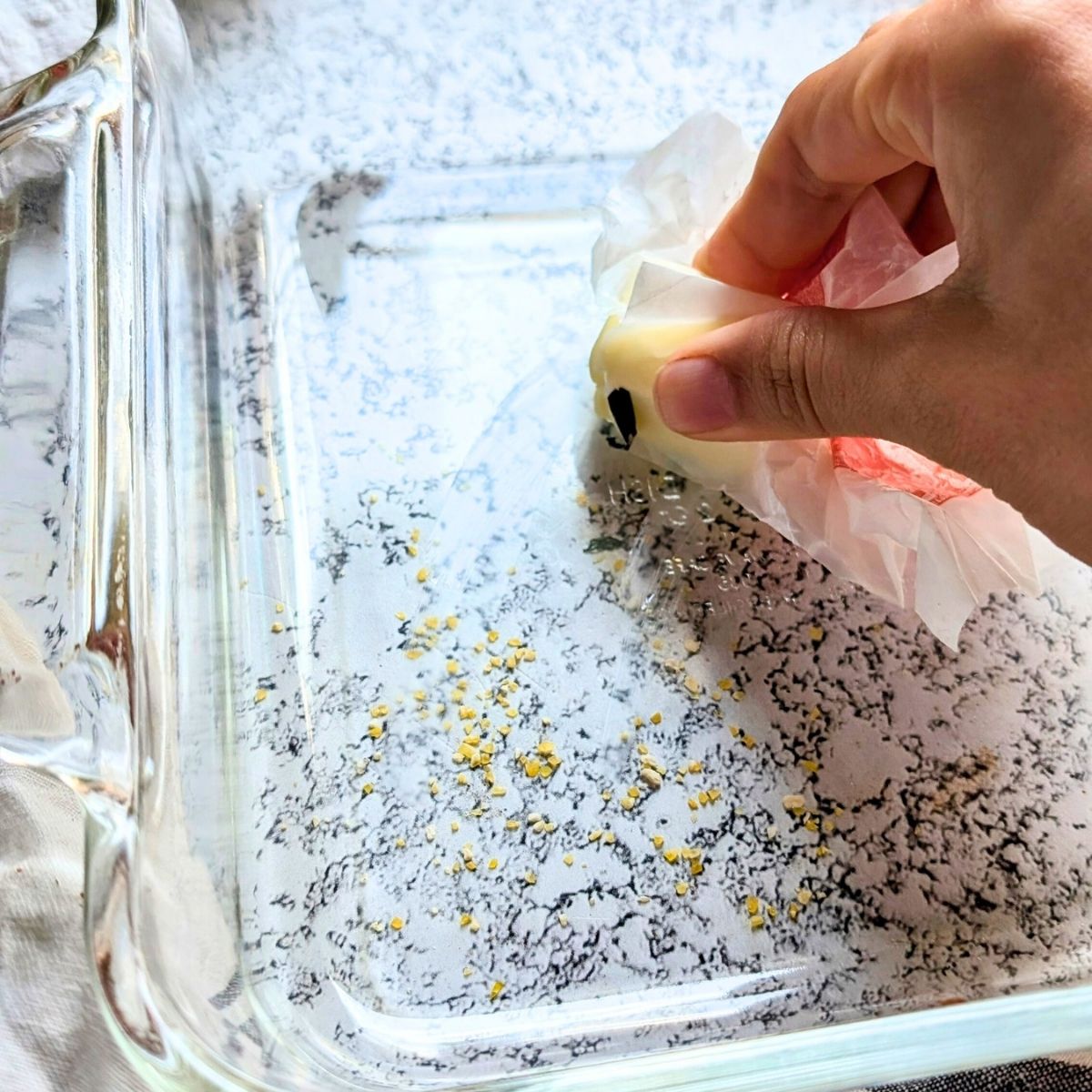 butter being rubbed in a baking dish to keep cornbread from sticking