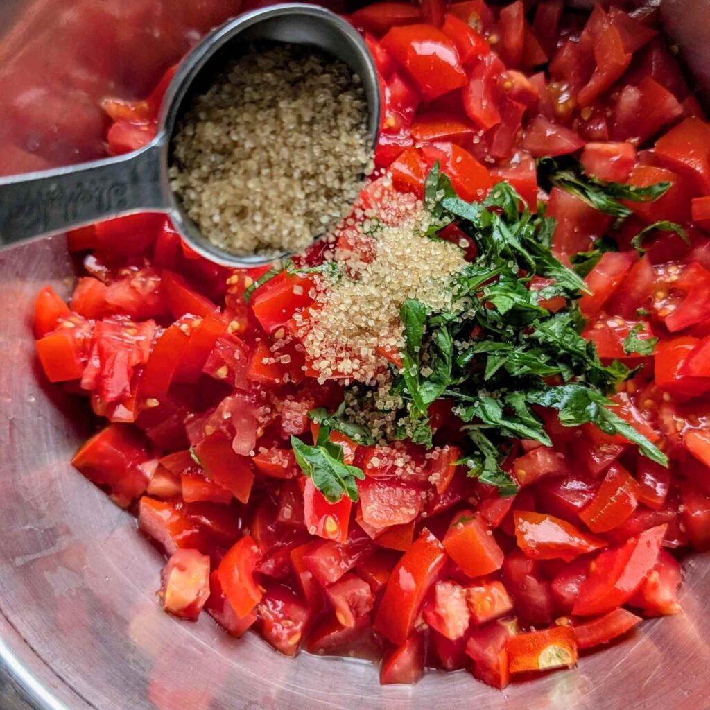 sugar and basil added to bruschetta in a bowl for an easy appetizer recipes