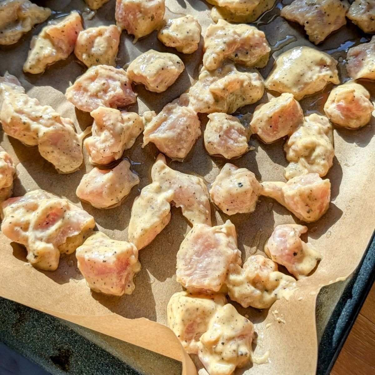 a sheet pan of chicken breasts coated in a batter to make crispy chicken bites in the oven