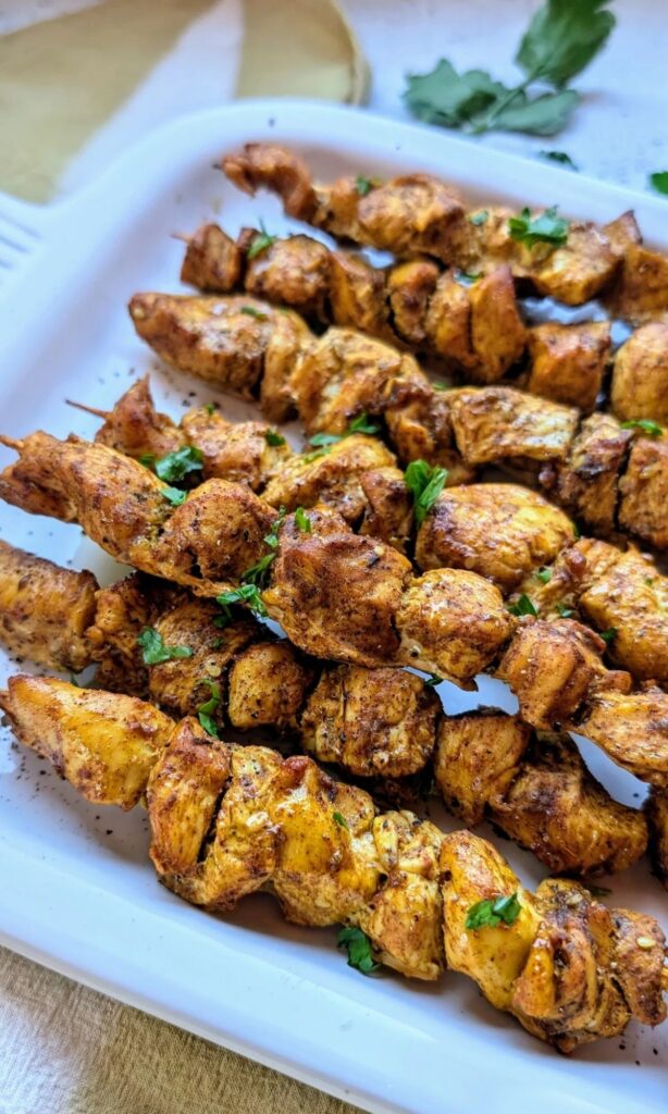 chicken shawarma skewers on a baking dish loaded with middle eastern and lebanese spices like turmeric, cinnamon, and cardamom.