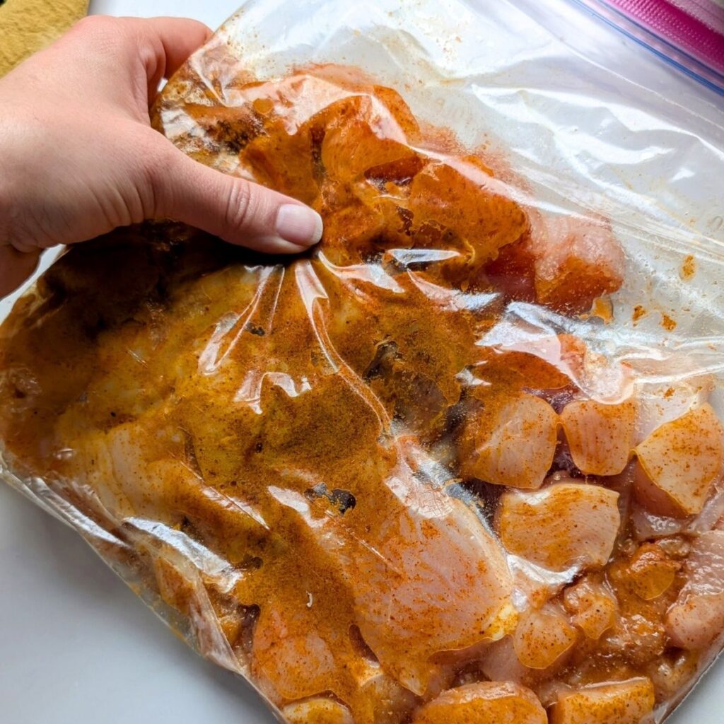 cubes of chicken breasts marinading in shawarma spices and vinegar to make oven baked shawarma at home.