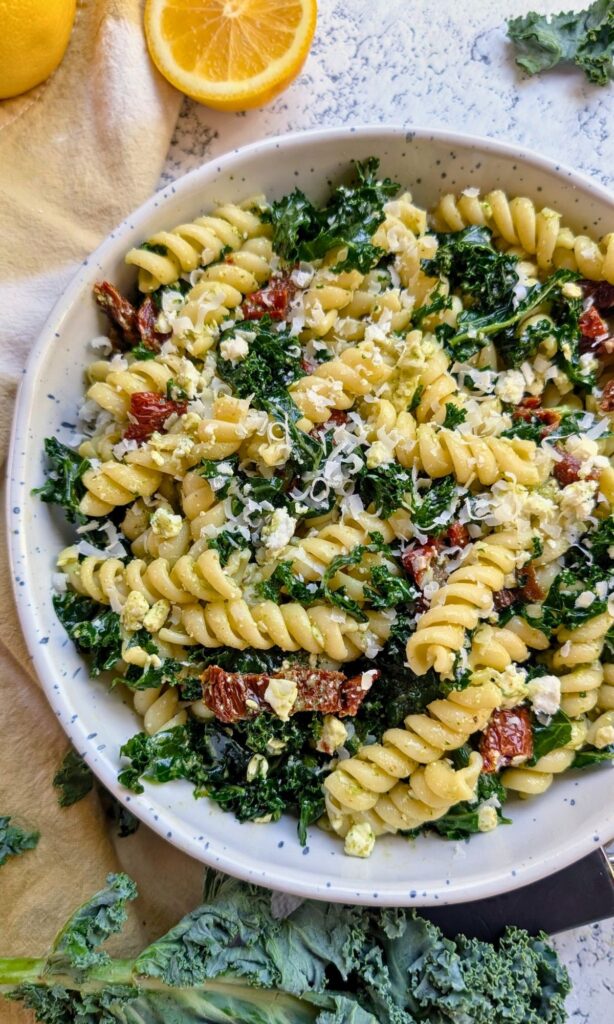 a large bowl of sam's version pasta salad with kale and fresh vegetables and tomatoes with homemade vinaigrette