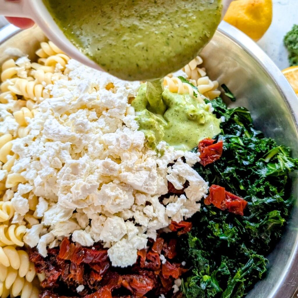 a large bowl of sam's club kale pasta salad copycat recipe with fresh garlic basil dressing poured on top.