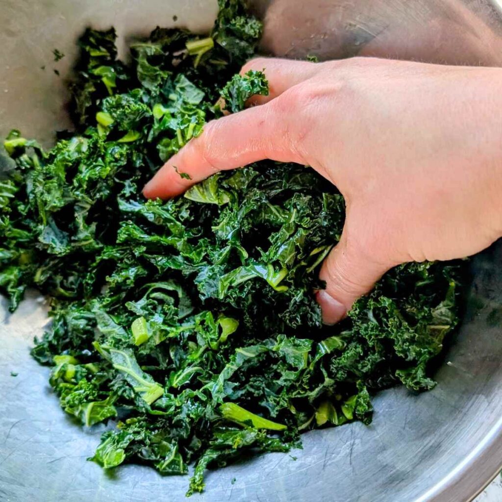 a hand massaging kale for pasta salad copycat recipes