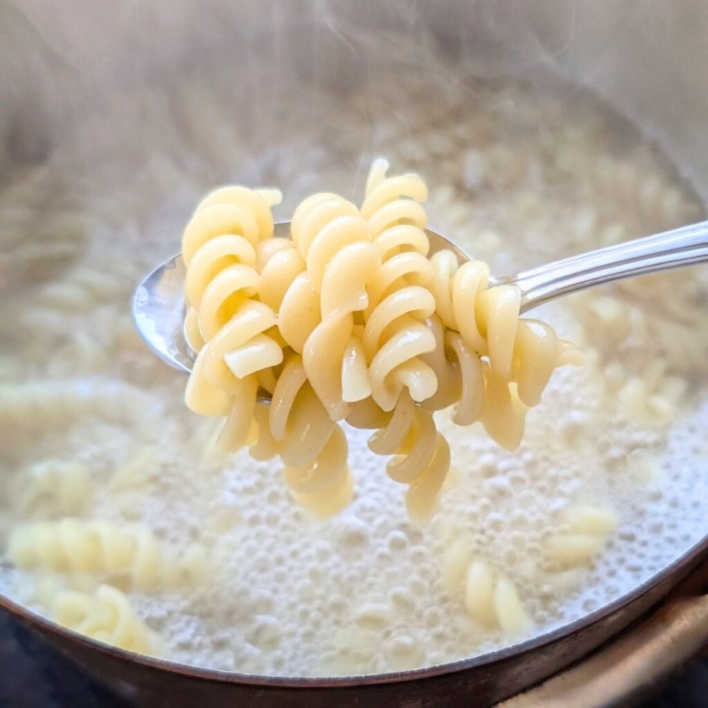 rotini pasta cooking in a pot of boiling hot water, ready to make pasta salad from sam's club.