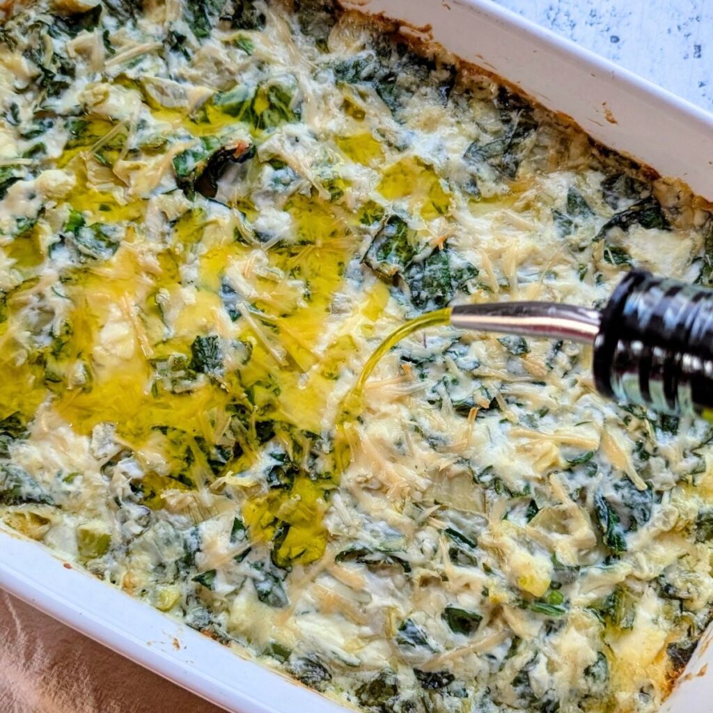 drizzled olive oil over italian artichoke heart dip with spinach and green onions with parsley and cheese.