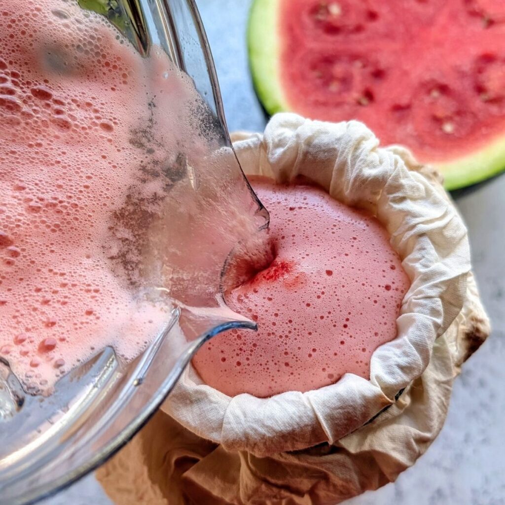 a large pitcher with cheesecloth straining out watermelon juice from the solids.