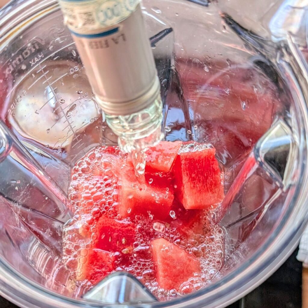 a blender with fresh watermelon chunks and white wine 