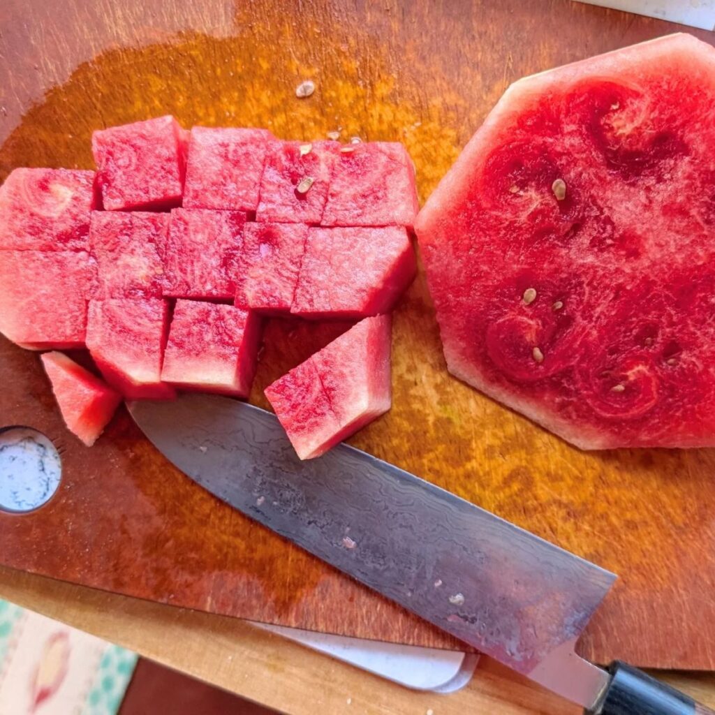 a knife chopping a fresh summer watermelon to make sangria