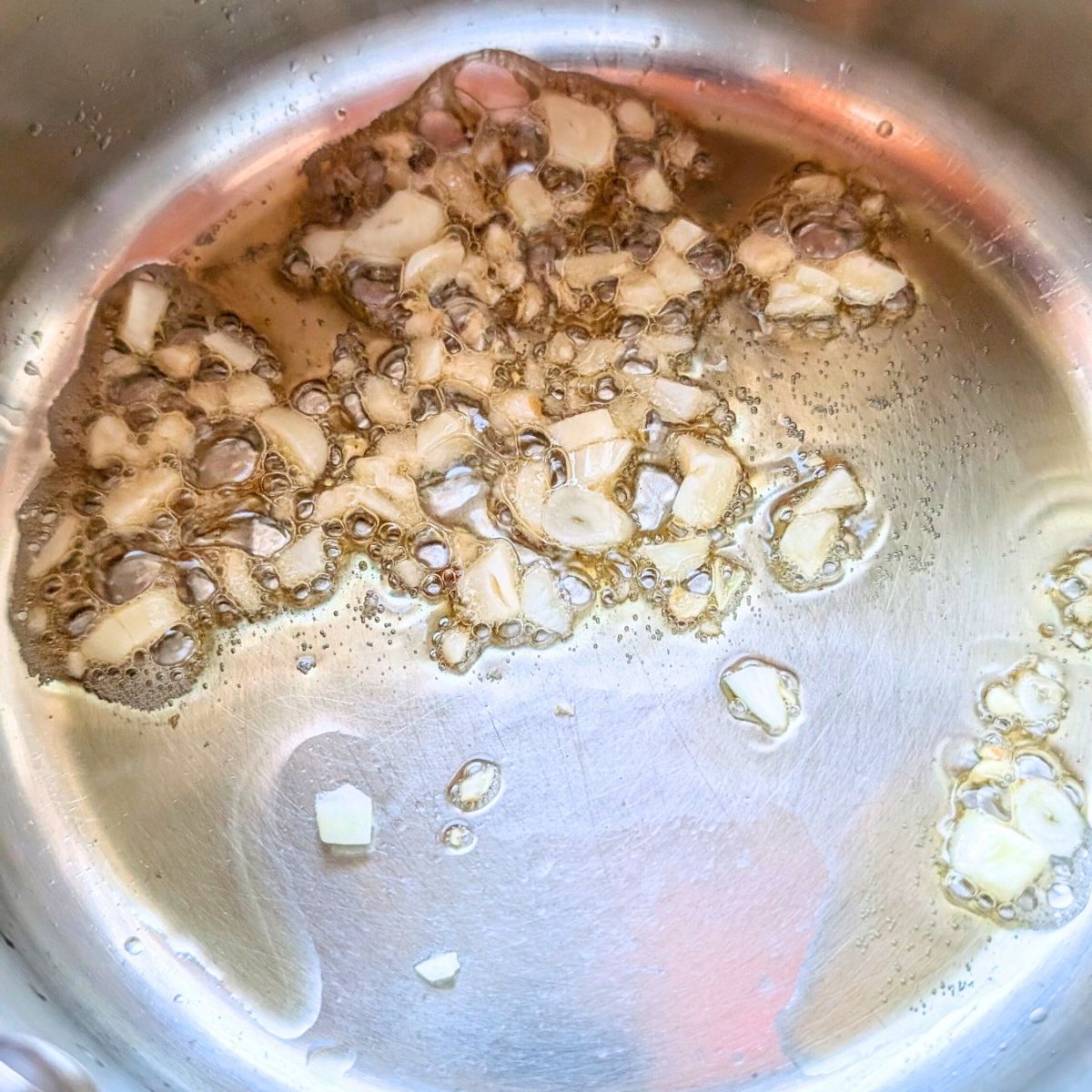 garlic and olive oil sautéing in a pan for alfredo with artichokes