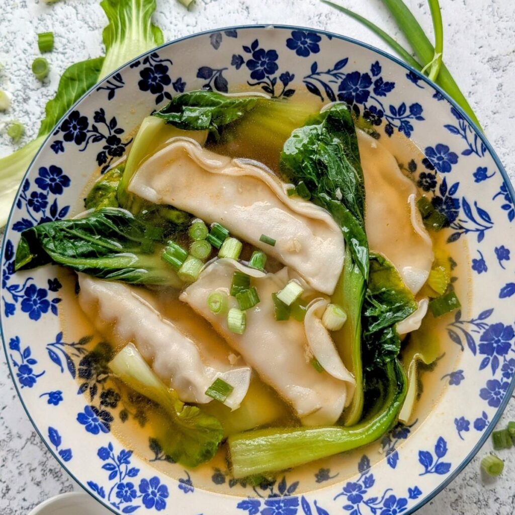 a bowl of dumpling and bok choy soup with soy sauce broth and frozen dumplings.