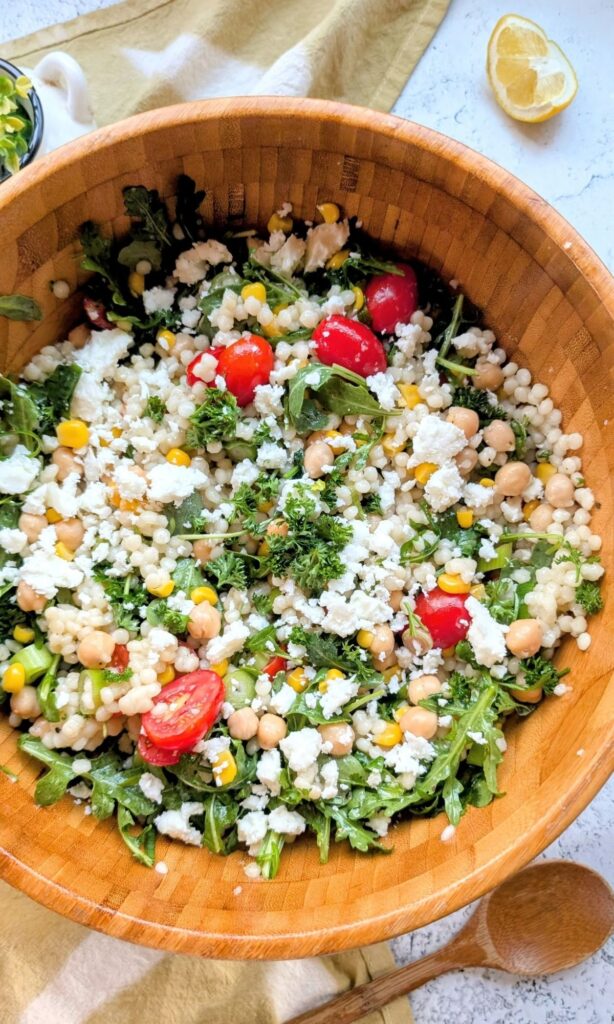 a large bowl of pearl couscous salad with lemon vinaigrette dressing with feta cheese and veggies.