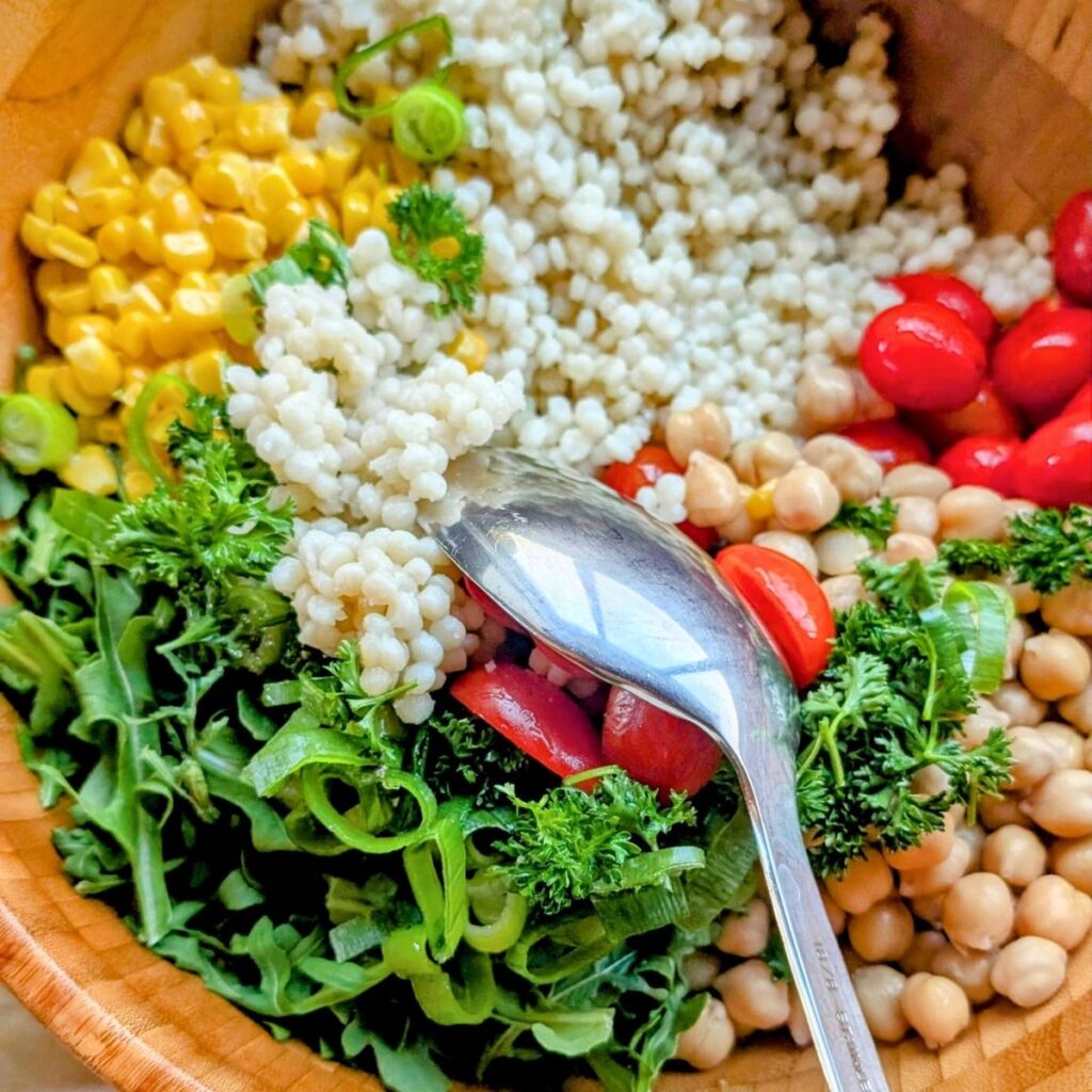 toss couscous salad with a spoon and lemon vinaigrette dressing with vegetables.