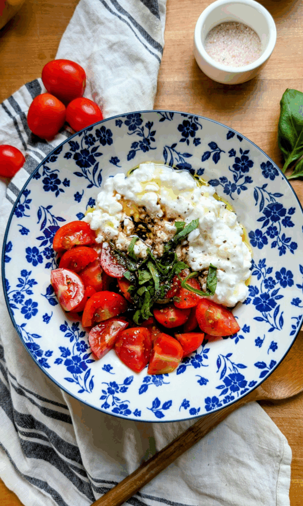 a large bowl with caprese salad with cottage cheese and no mozzarella with basil and tomatoes.