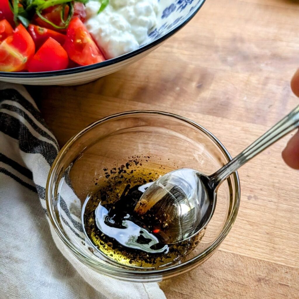 a small bowl with balsamic vinegar salad dressing for a cottage cheese Caprese bowl