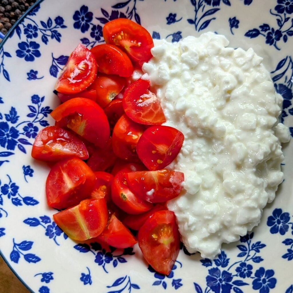 a bowl of cottage cheese and sliced cherry tomatoes for a high protein lunch