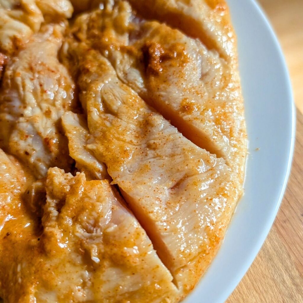 mango marinated chicken breasts scored with a knife to help with cooking.