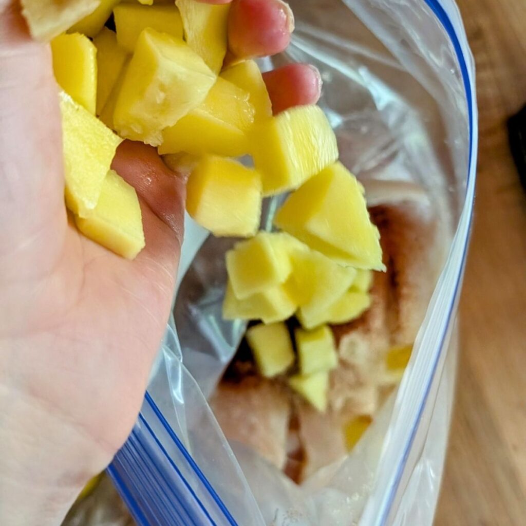 diced mango in a bag with chicken for a mango lime marinade.