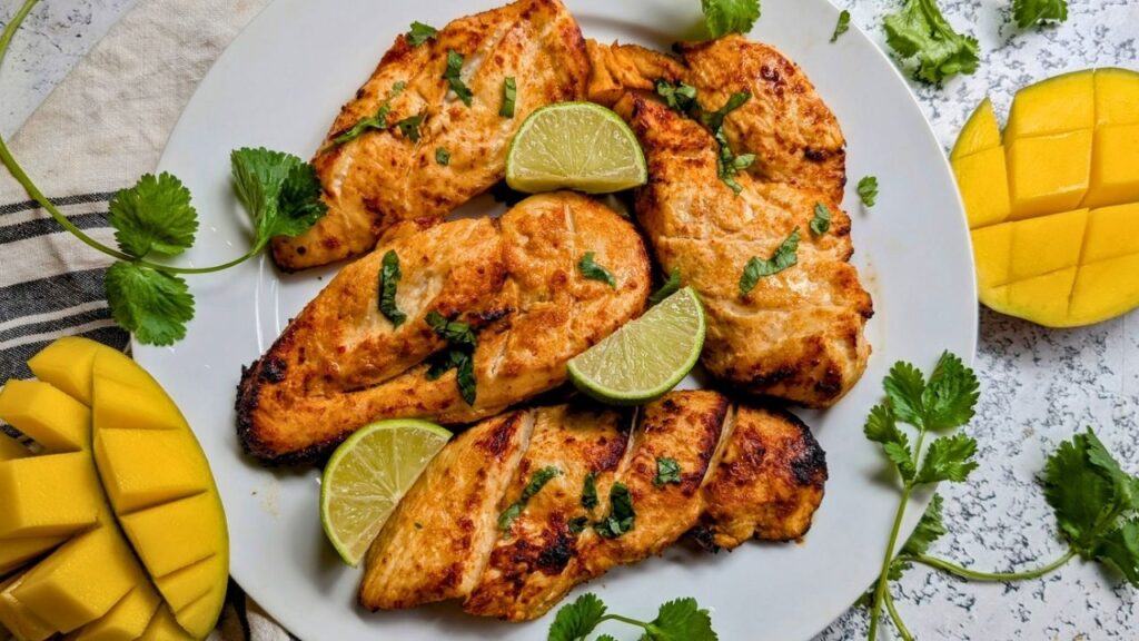 a plate of cooked mango lime chicken with fresh mango slices and cilantro