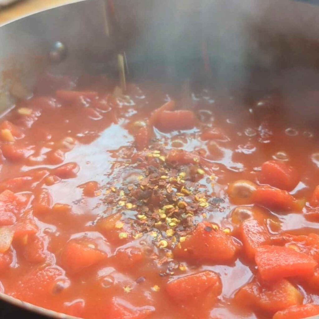 simmering pot of tomatoes with chorizo and fresh herbs.